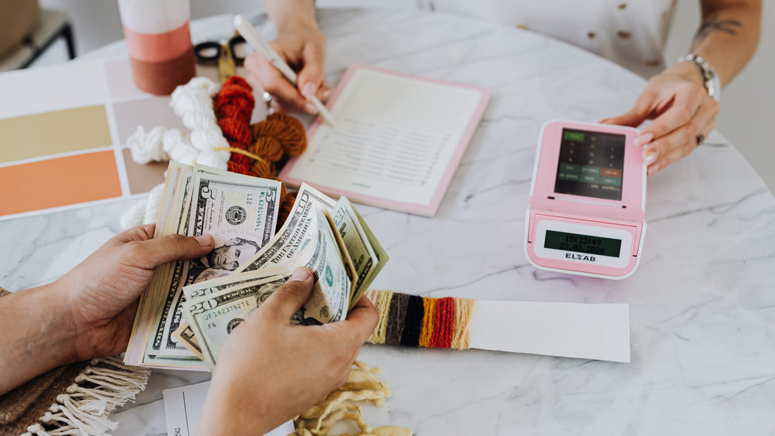 two people sitting at a table creating a budget plan with a calculator 